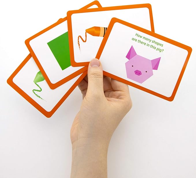 Hand holding educational flashcards with shapes and questions on a white background
