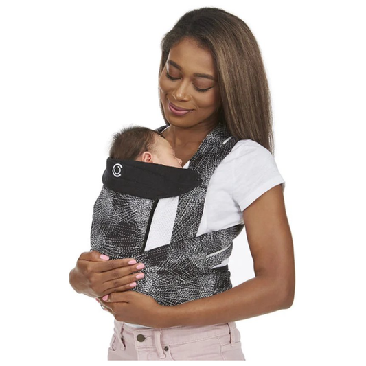 Woman holding a baby in a black and gray baby carrier against a white background